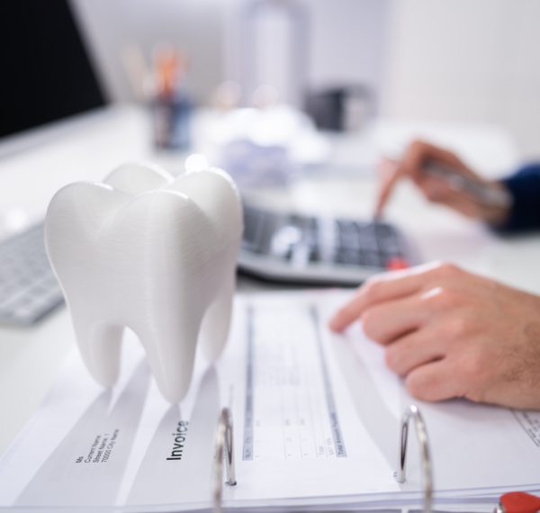 Close-up Of Tooth In Front Of Businessperson Calculating Bill